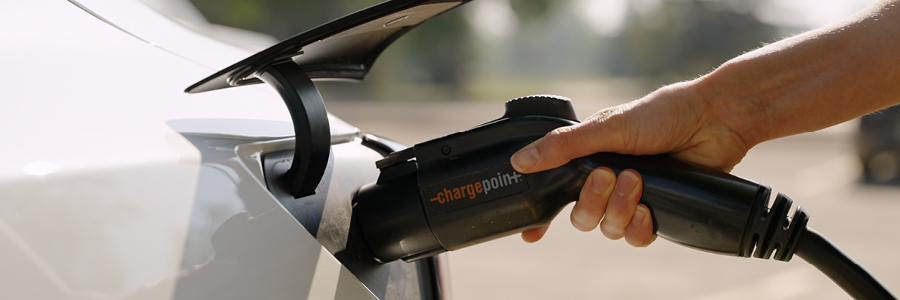 A hand plugs an electric vehicle charger into the car