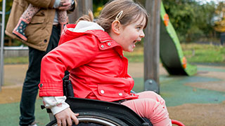 Girl in a wheelchair crossing a playground