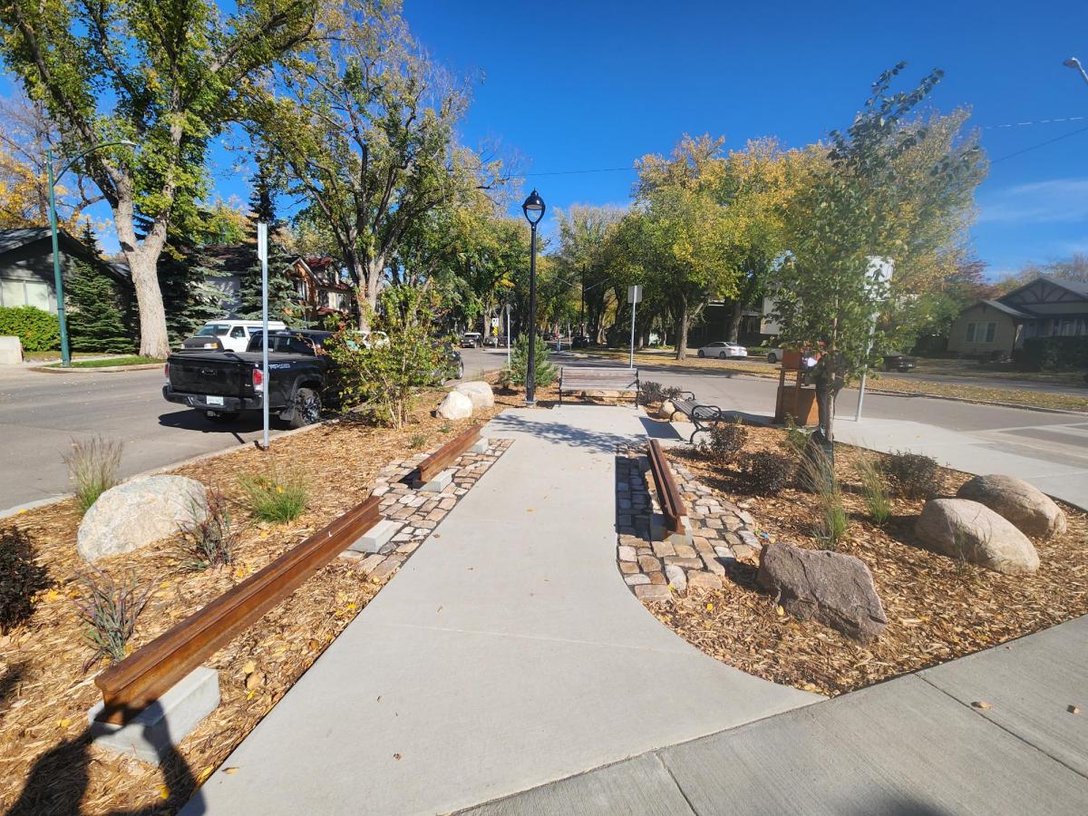 Image showing 14th Street parklet after construction during the day. The parklet feature decorative heritage rails, new concrete walkway, plantings, benches, bike racks, and lighting.