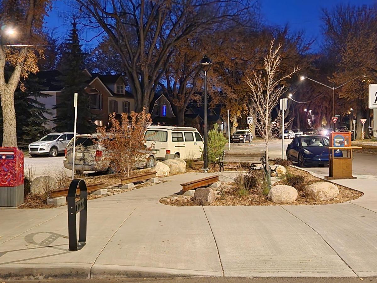 Image showing 14th Street parklet after construction at night. The parklet feature decorative heritage rails, new concrete walkway, plantings, benches, bike racks, and lighting.